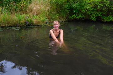 Fototapeta premium A person enjoys a refreshing swim in a tranquil pond, enveloped by vibrant plants and trees, creating a peaceful escape in the heart of nature in Russia.
