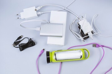 Electronic chargers and cables, power banks and flashlight on table 