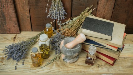 Healing herbal remedies, ancient books, bouquets of mystical herbal potions and candles on wooden background