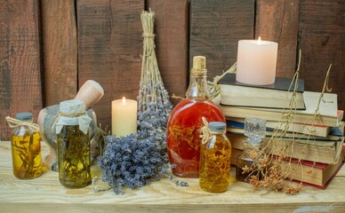 Healing herbal remedies, ancient books, bouquets of mystical herbal potions and candles on wooden background