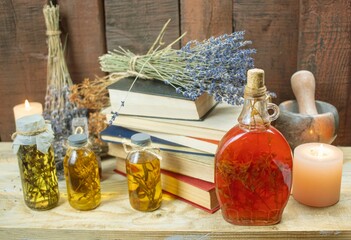 Healing herbal remedies, ancient books, bouquets of mystical herbal potions and candles on wooden background