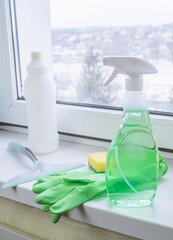 Window cleaning products on a windowsill with a view of a snowy winter