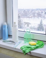 Window cleaning products on a windowsill with a view of a snowy winter