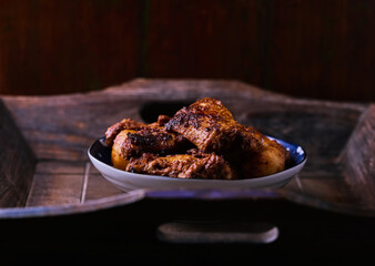 Fried chicken wings with potatoes on a rustic background. Soft focus.
