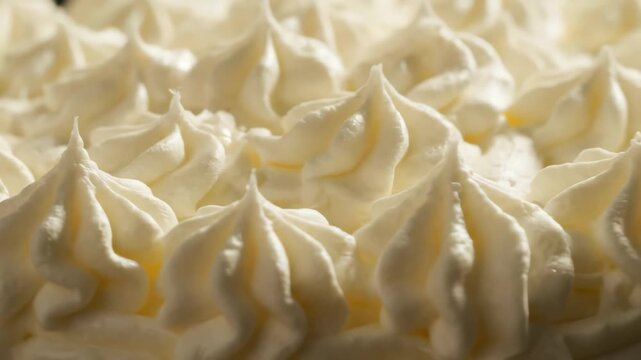 Delicious macro detail of numerous pale cream icing swirls and peaks on a sweet dessert, concept for bakery branding, dessert menu design and sweet confectionary advertising