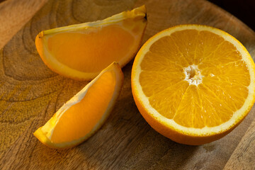 An orange cut in half on a wooden tray illuminated by a beam of light