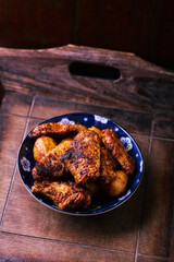 Fried chicken wings with potatoes on a rustic background. Soft focus.
