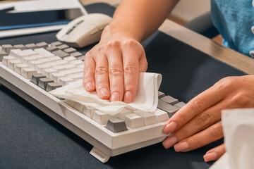 Beautiful women's hands with manicures carefully wipe the keyboard keys with a white paper napkin....