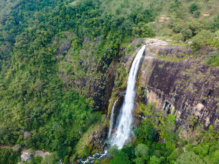 Obraz premium Aerial view of Diyaluma Falls in Sri Lanka. Powerful waterfall cascading through lush green landscape, dramatic natural scenery, tropical nature and adventure travel destination seen from above.