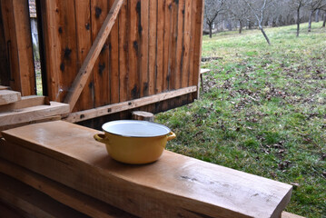 Yellow enamel pot on rustic wooden beams outdoors