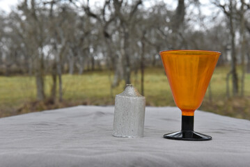 Orange glass stemmed goblet and silver textured candle for a unique outdoor or indoor decorative display