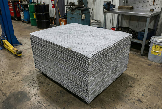 Stack of gray industrial oil absorbent pads for spill containment