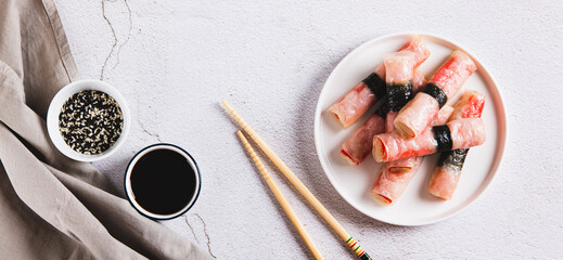 Fried spring rolls with crab sticks and nori on a plate on the table top view web banner