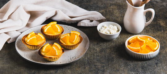 Mini baked tarts with cottage cheese and orange on a plate on the table web banner