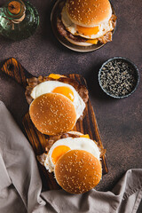 Breakfast sandwich with egg, bacon and cheese on a board on a table top and vertical view