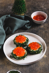 Creative mini sandwiches with red caviar, butter and dill on a plate on the table vertical view