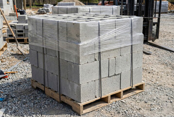 Pallet of concrete cinder blocks wrapped in plastic on a construction site