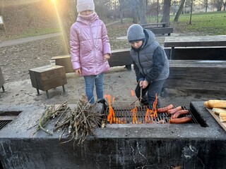 Children grilling sausages on a fire