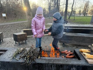 Children grilling sausages on a fire