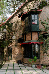 Charming Old Stone House with Bay Window and Lush Greenery, Inviting and Peaceful Exterior, Architectural Detail, Ideal for Travel and Real Estate Concepts