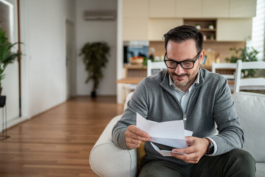 Man reading letter at home feeling joyful