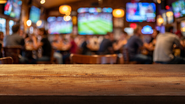 blurred busy interior of sports bar and wooden countertop in foreground
