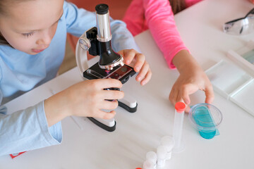 A girl examines microorganisms under a microscope in a biology lesson