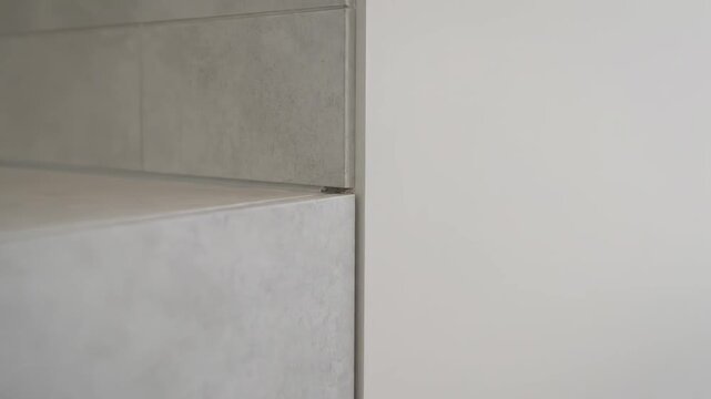 Minimalist gray kitchen drawer smoothly opening. Modern furniture detail with a push to open system and handleless cabinet facade