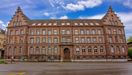 Fototapeta premium Front view of the historic Gewerbemuseum Basel showing symmetrical architecture, stone facade, and classic urban design.