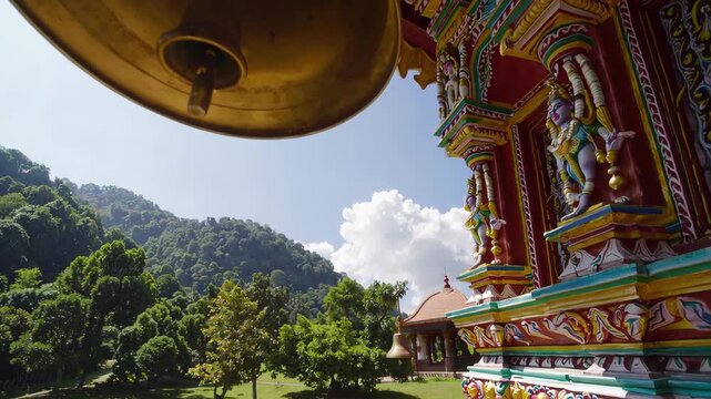 Bells hanging from colorful hindu temple with mountain and green trees in background, traditional architecture and religious artifact, maha shivaratri