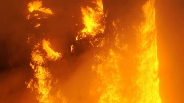 Intense vertical fire blaze transitioning into dark smoke columns