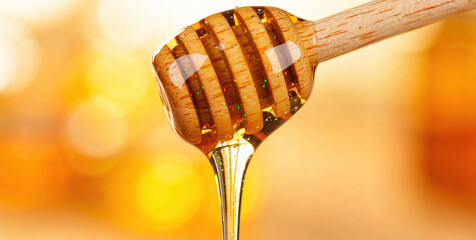 Golden Honey Dripping from Wooden Spoon with Blurred Orange Background