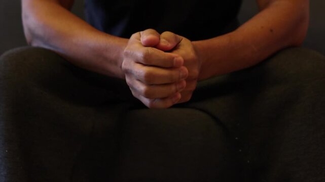 Person nervously fidgeting with clasped hands