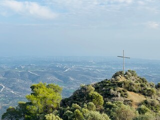 Large cross on the mountain near Holy Monastery of Stavrovouni, Cyprus, standing against the sky as a symbol of faith, Orthodox tradition, pilgrimage, and dramatic rocky landscape