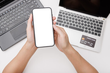 Hands using smartphone mockup on office desk. Blank screen mobile phone for graphic display montage