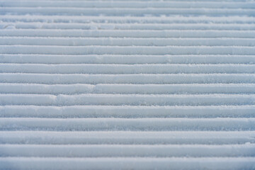 Beautiful winter background with snow-covered ground. Rhythmic linear patterns and winter texture on snow. Made snow texture. Wide panoramic texture for background and design. Close-up view from above