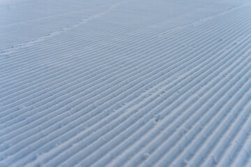 Beautiful winter background with snow-covered ground. Rhythmic linear patterns and winter texture on snow. Made snow texture. Wide panoramic texture for background and design. Close-up view from above