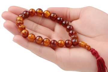 Hand holding amber prayer beads isolated on transparent background