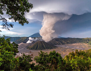 Dramatic landscape featuring an active volcano erupting a massive ash plume into swirling clouds. Framed by lush foliage, this powerful image represents nature’s raw energy and majesty.
