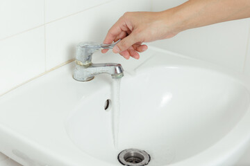Hand turning off tap in bathroom - save water concept - ecological and environmental concepts