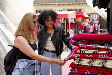 Women shopping for handmade textiles at an outdoor market
