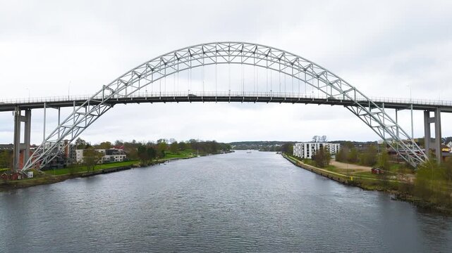 centered elegant steel arch bridge spanning glomma river calm water green banks modern housing define fredrikstad norway drone view urban infrastructure crossing 