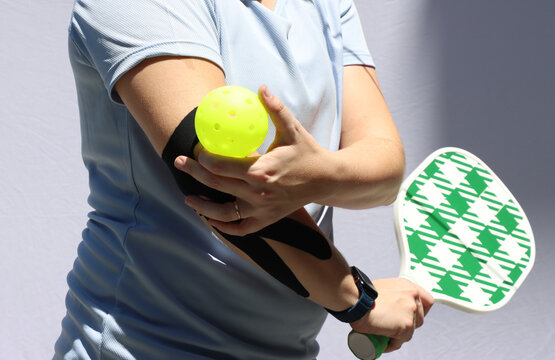 Caucasian woman playing pickeball with a Kinesio in the elbow and with pain in the elbow