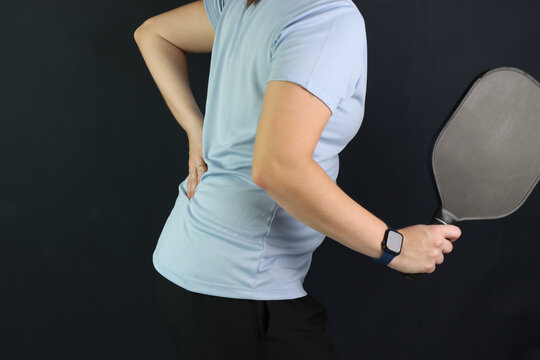 Caucasian woman playing pickeball with a lumbar pain and putting the hand in the pain region