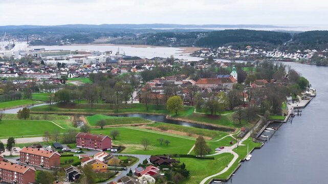 looks across green ramparts moats along glomma river red roofed buildings paths layered hills shape fredrikstad norway drone view historic fortifications defensive aerial 