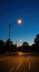 Bright street light turning on at dusk providing essential illumination for the empty roadway, housing, street, security