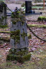 fence pole with carved Christian cross and rusty chain in cemetery