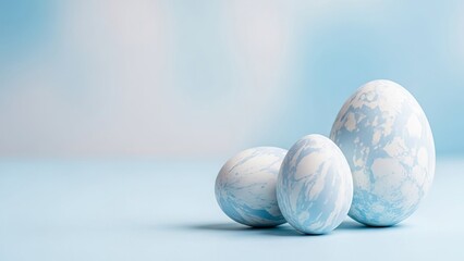 Three Marbled Easter Eggs in Soft Blue and White Hues on a Light Blue Surface marbled eggs