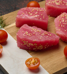 Raw tuna pieces in sesame seeds on a cutting board
