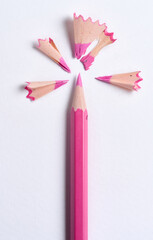 Wooden shavings and pink pencil on white background, top view